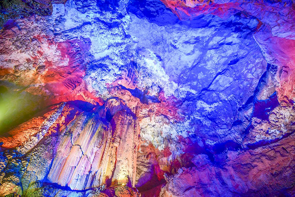 Sunlight filtering through hidden openings casts magical glows, turning the cave into a surreal underground wonderland